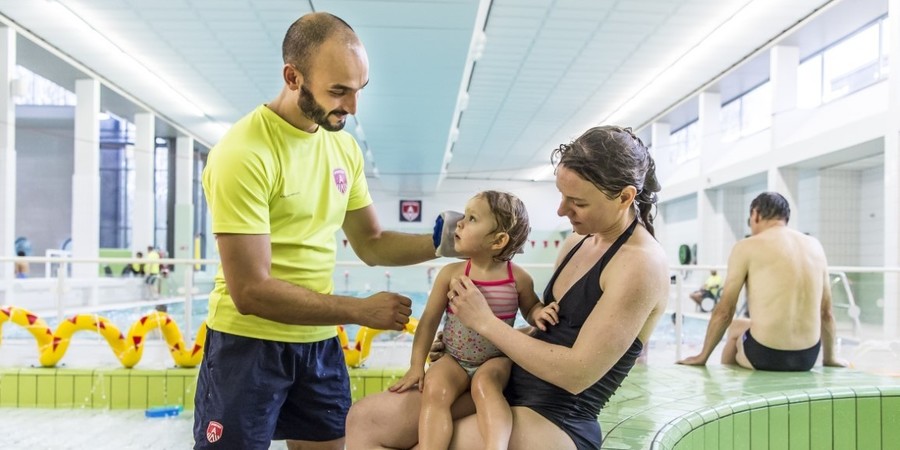 redder verzorgt kind in zwembad